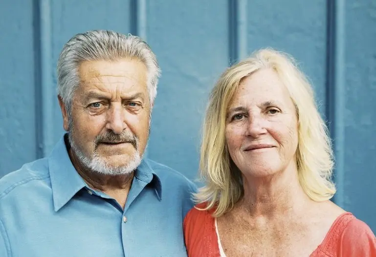 Portrait of an elderly couple smiling gently at the camera.