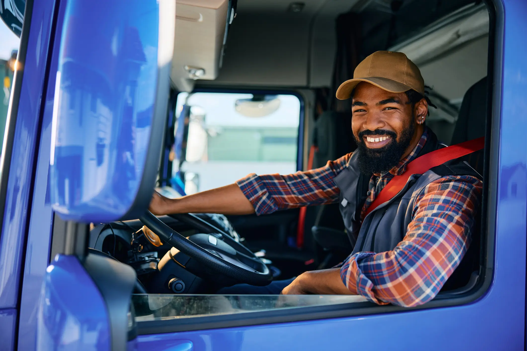 Smiling truck driver sitting in the cab, ready to drive.