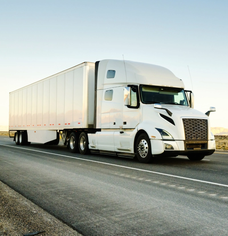 White semi-truck driving on an open highway.